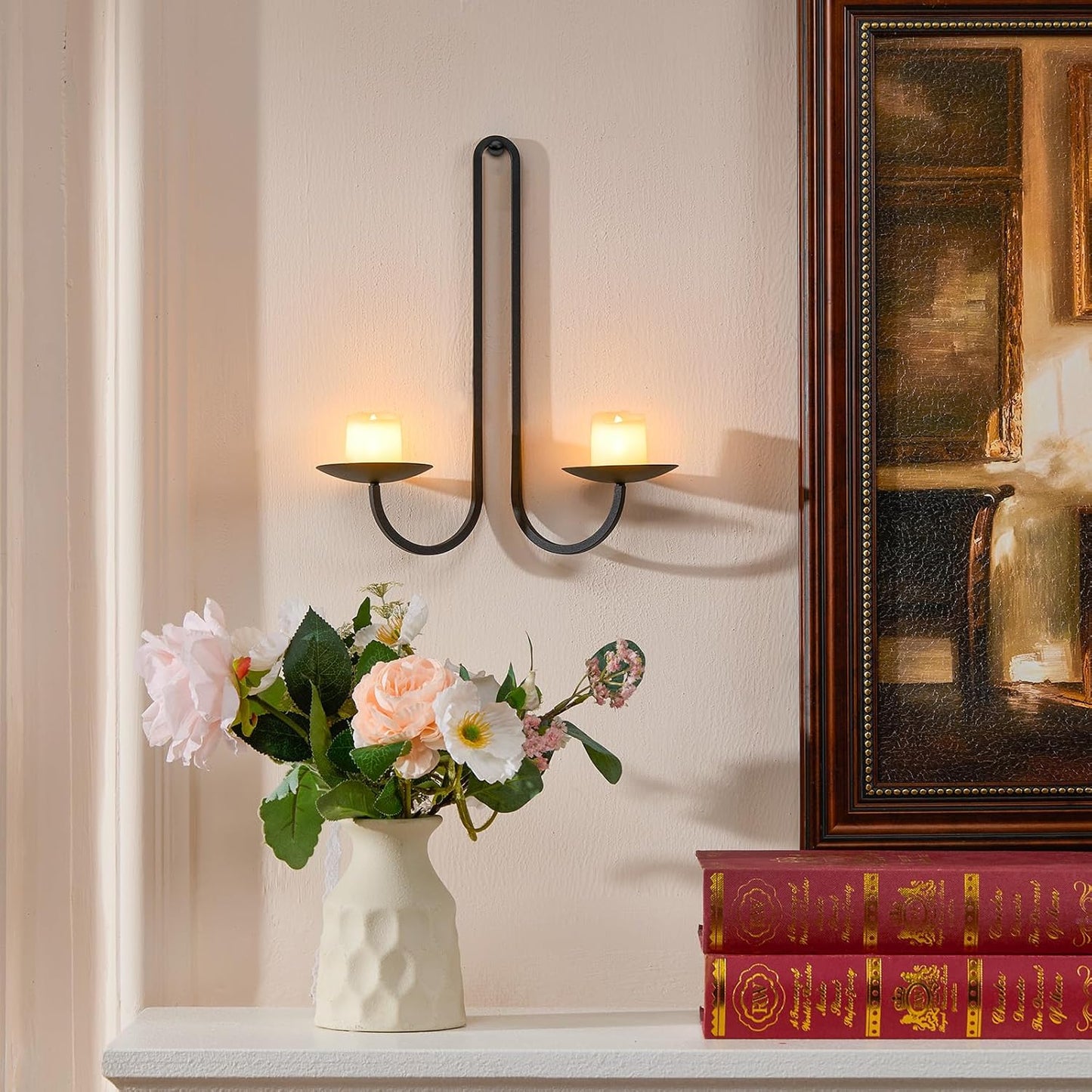 Decorative wall sconces with candles, a vase of flowers, and books on a shelf.
