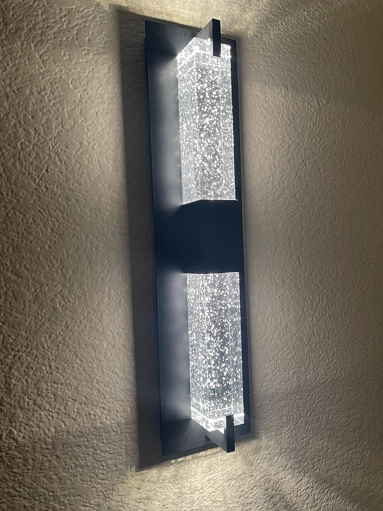 Modern wall sconce with crystal accents on a textured wall.
