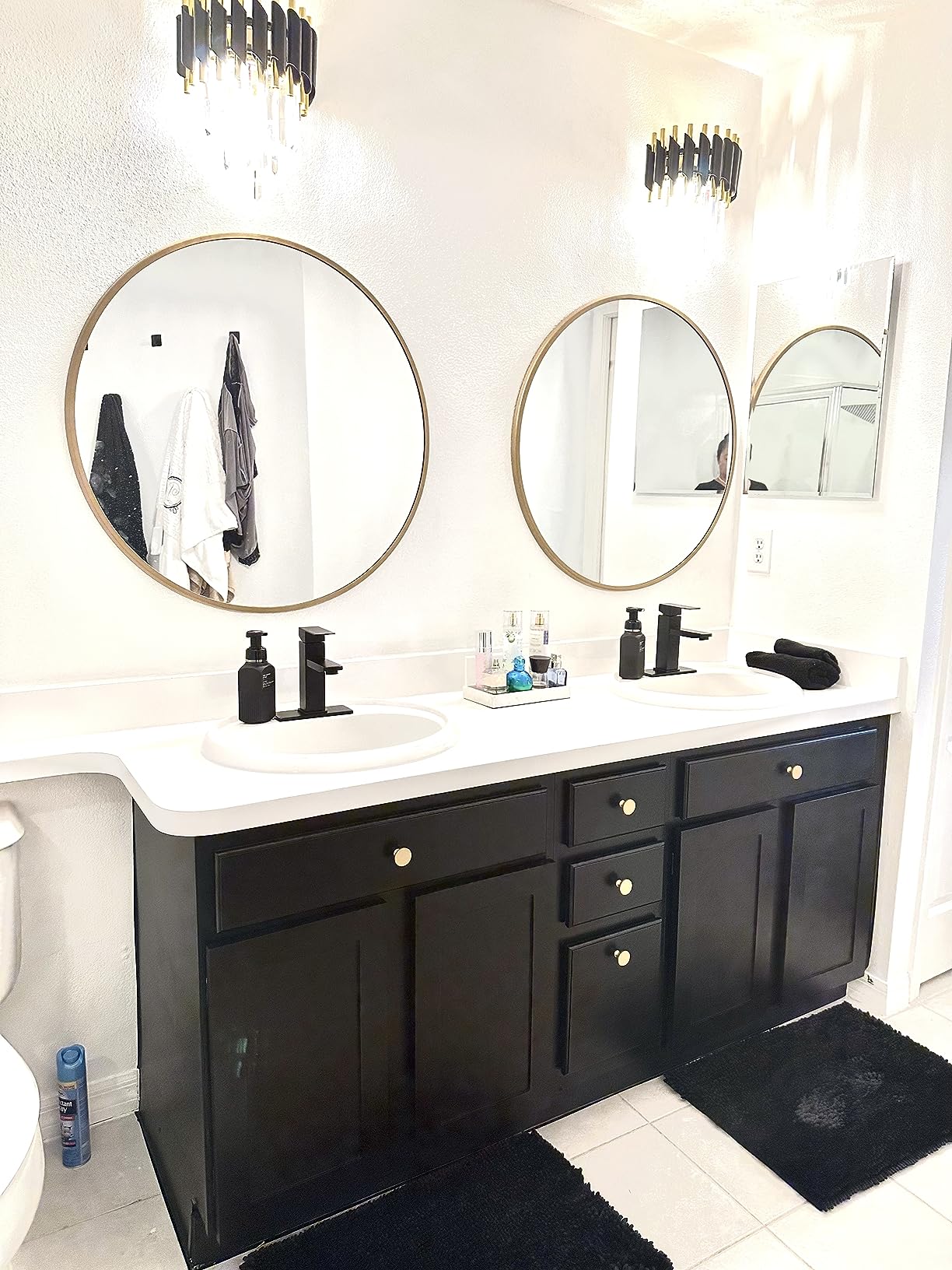 Bathroom with black vanity, round mirrors, and white countertop.