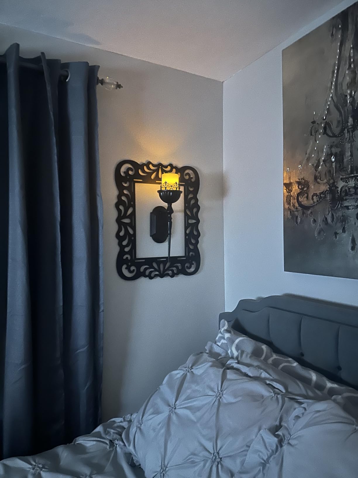 Bedroom with decorative mirror, wall sconce, and large painting on the wall.