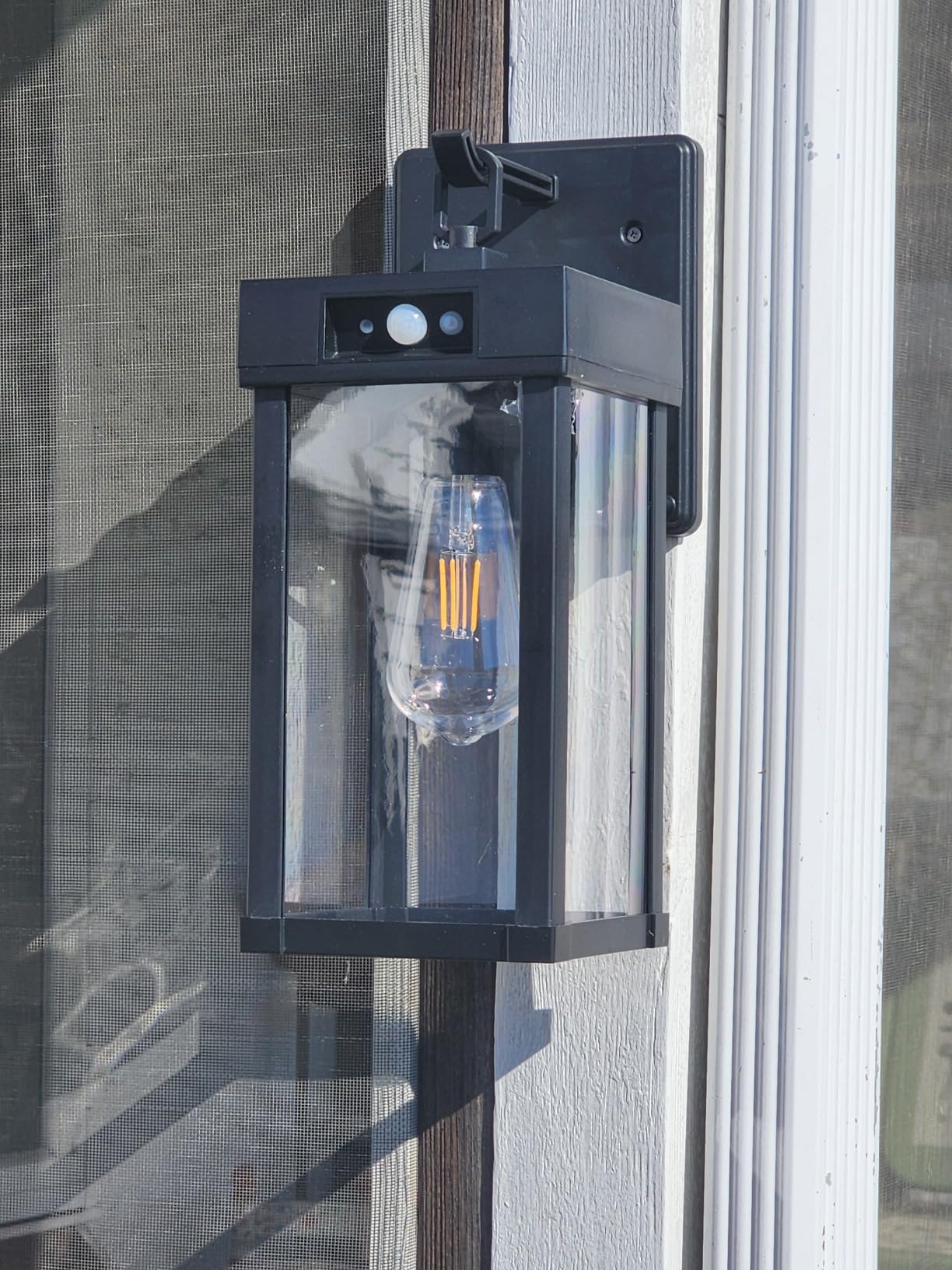 Black outdoor wall light fixture attached to a house exterior.