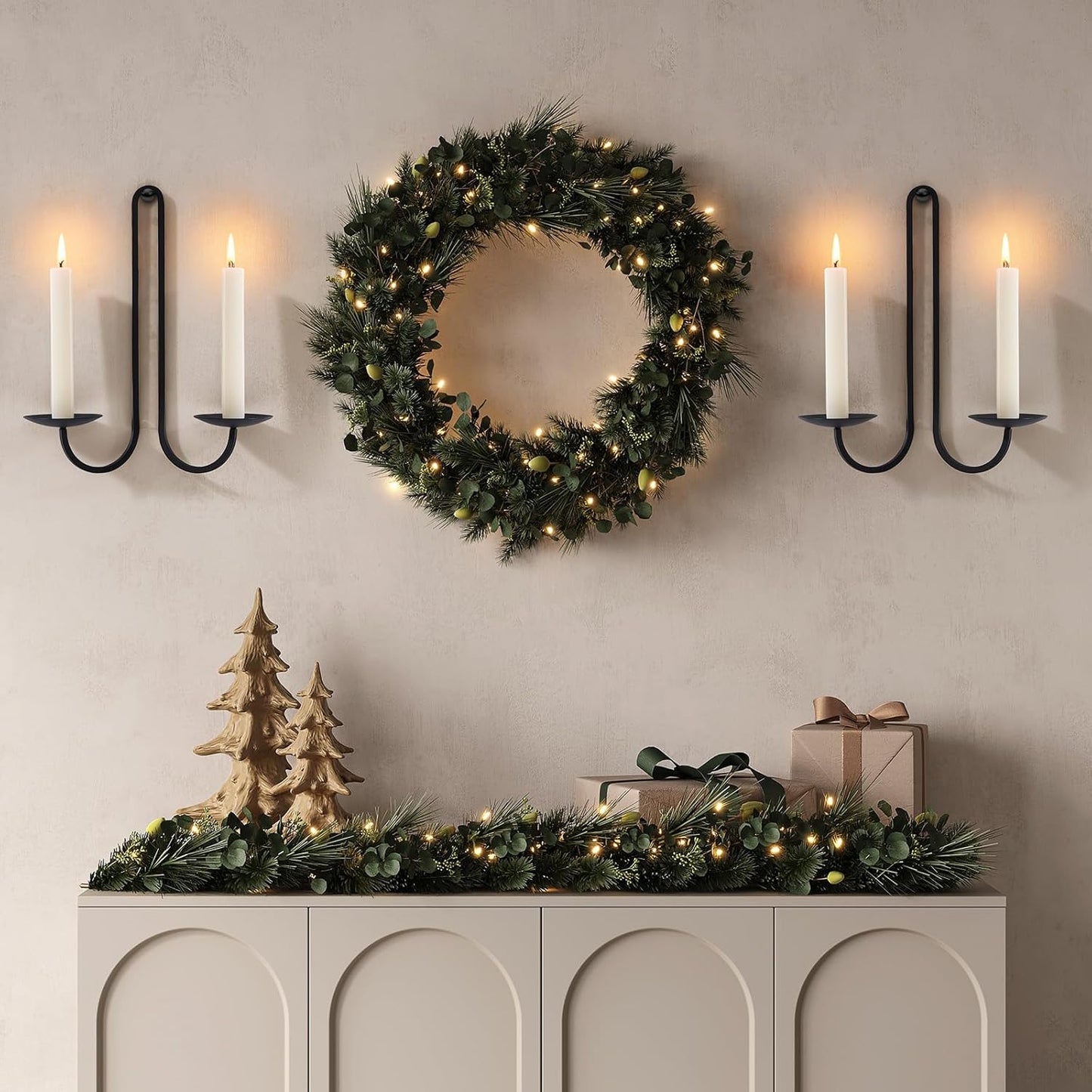 Decorative setup with a wreath, candles, and Christmas trees on a wall.