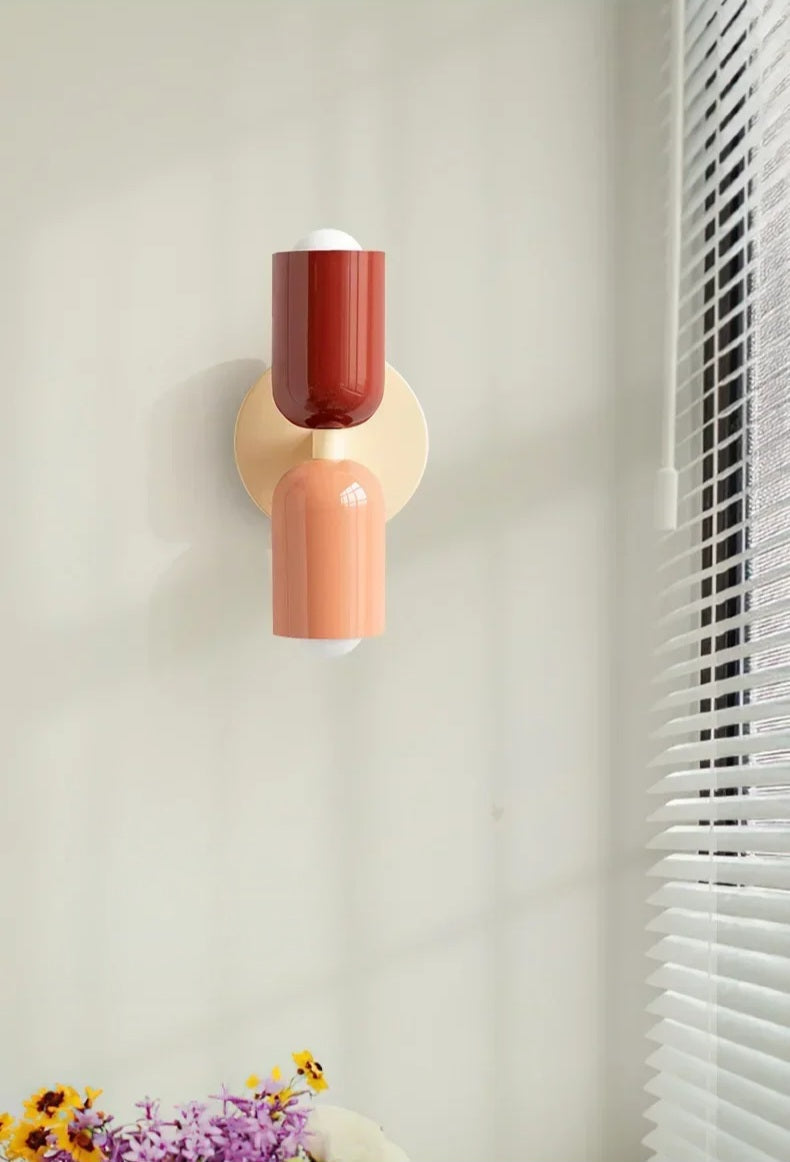 Decorative wall light fixture with a red and beige design on a neutral wall.