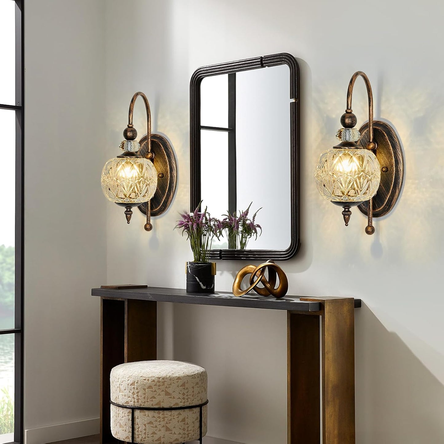 Decorative wall lights with a mirror and console table in a room setting.