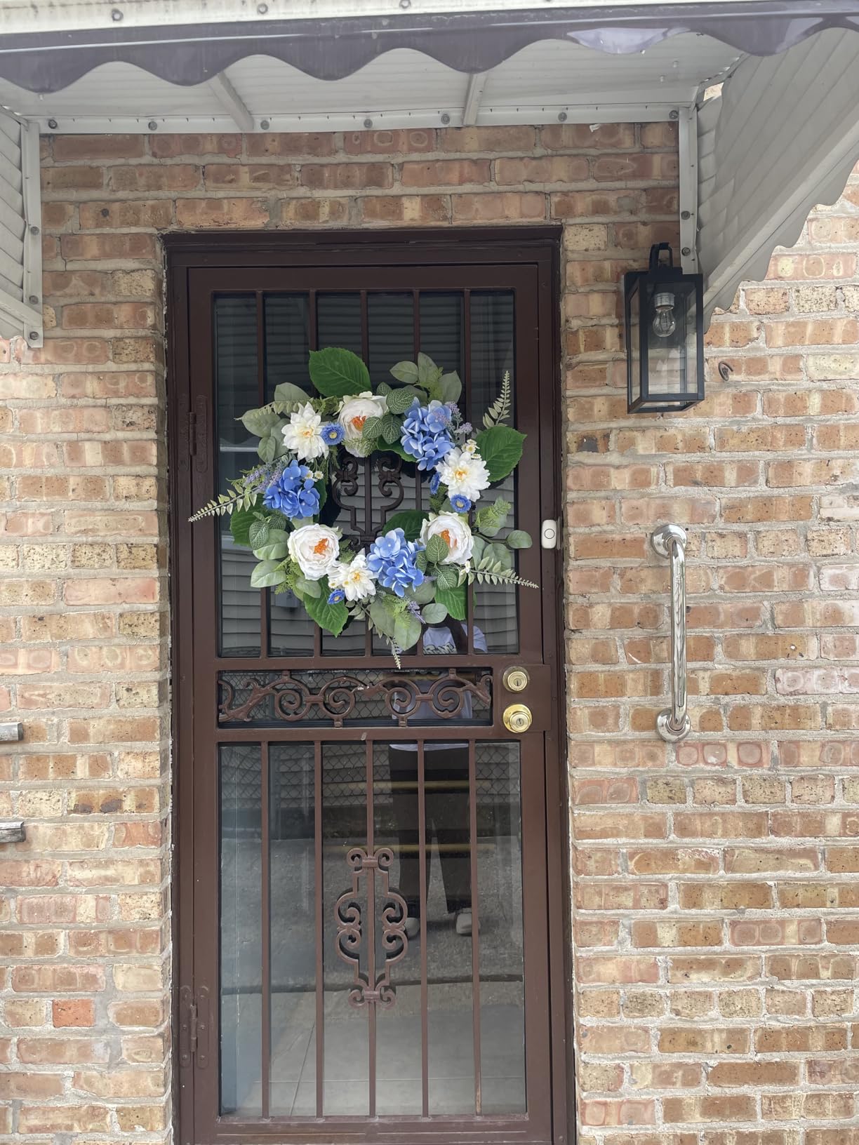 Decorative wreath with flowers on a door of a brick house