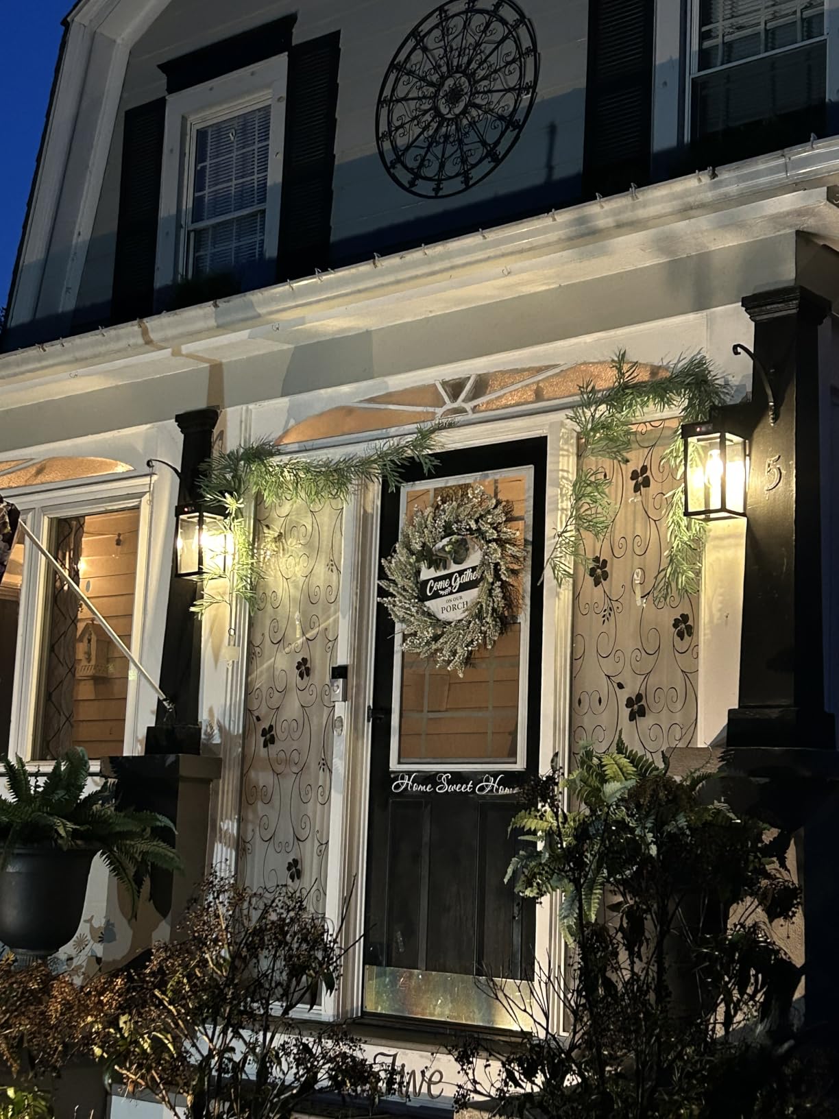 Front door of a house with wreath and decorative lights at night