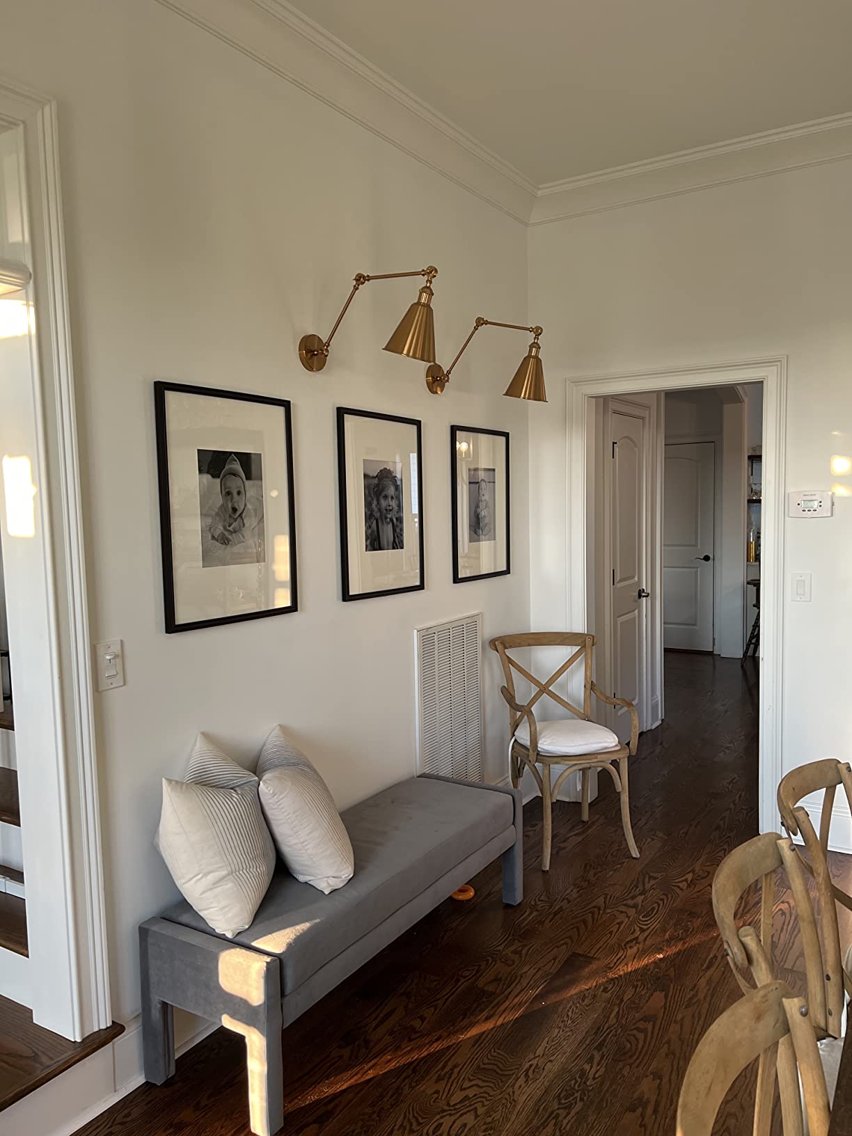 Living room with gray sofa, wooden chairs, and wall art.