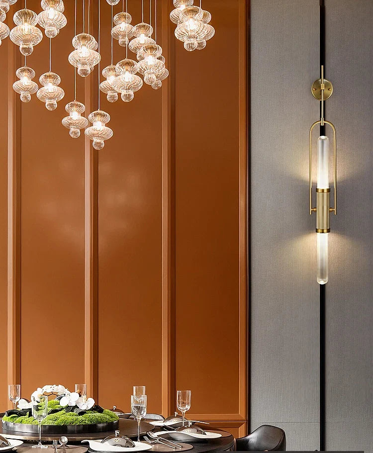 Modern chandelier and wall sconce in a dining room setting with a table and decor.