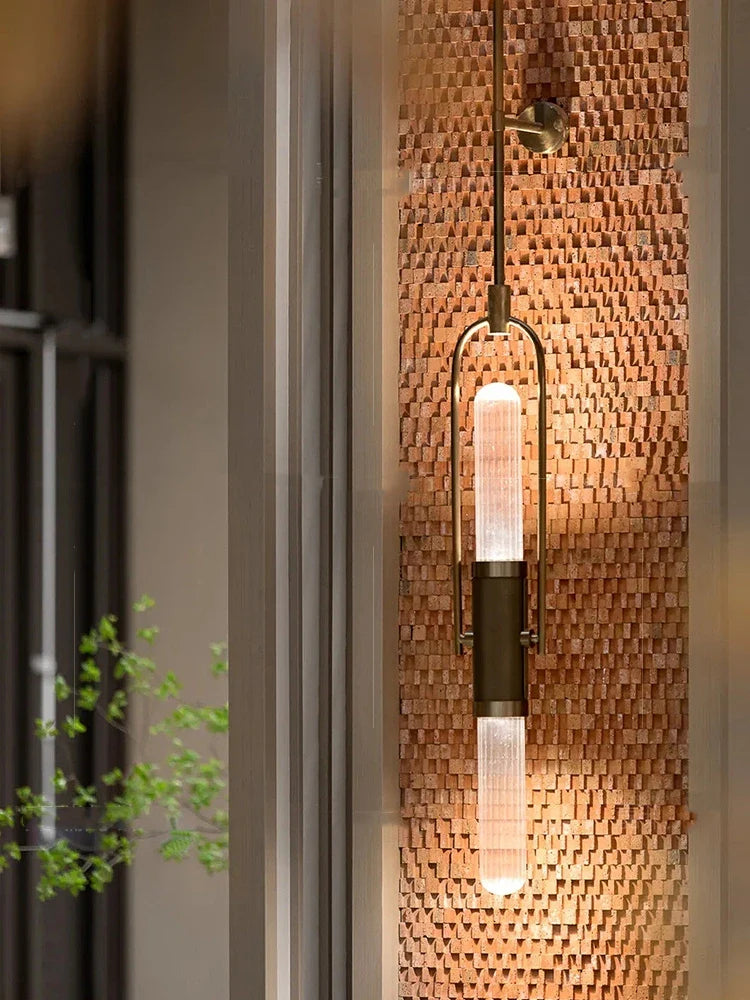 Modern pendant light fixture on a textured wall with a plant in the background