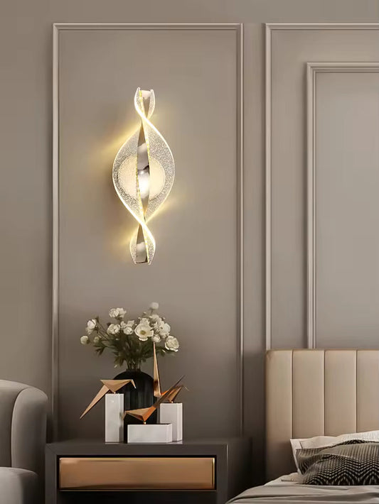 Modern wall sconce in a bedroom setting with a vase of flowers on a nightstand.