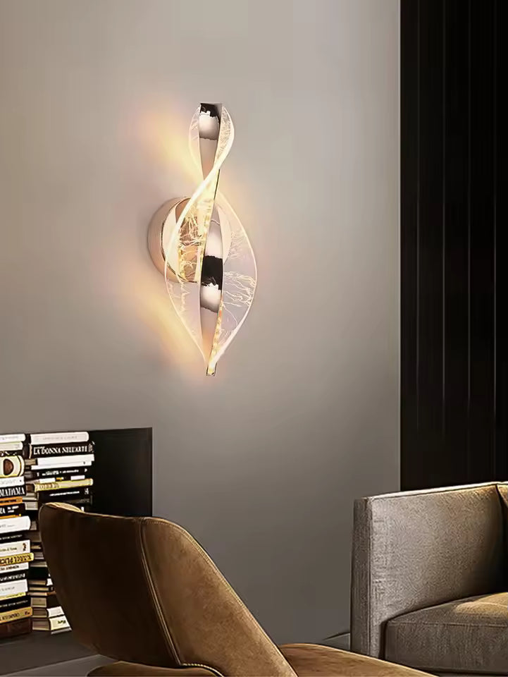 Modern wall sconce in a living room setting with books and a chair.