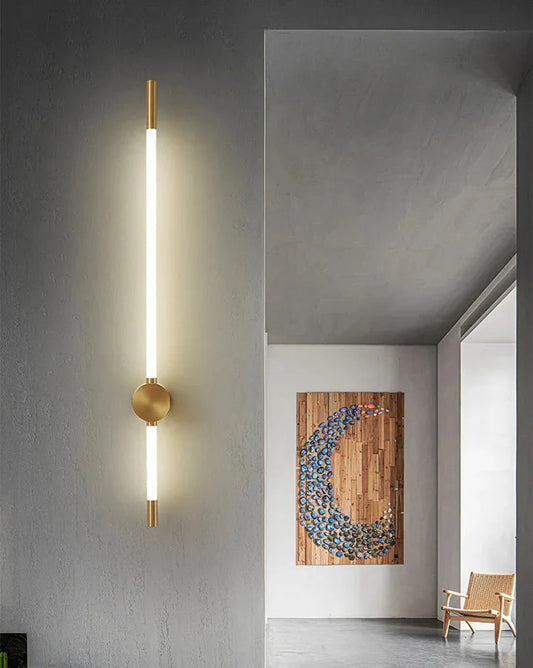 Modern wall sconce on a gray wall with a decorative piece and chair in the background