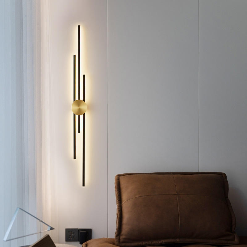 Modern wall sconce with a gold bulb on a light gray wall next to a brown pillow.