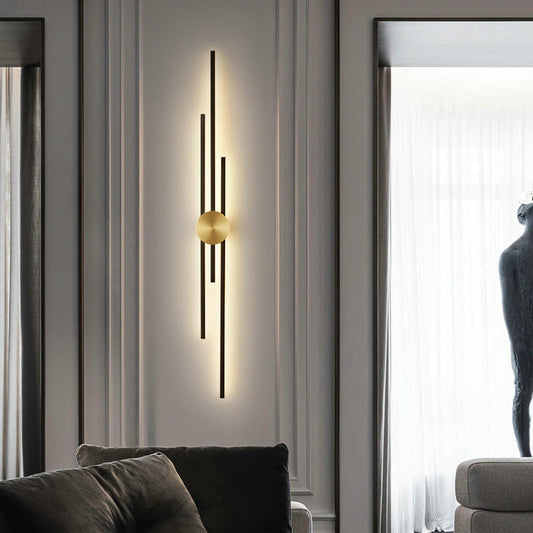 Modern wall sconce with gold bulb on a gray wall in a living room setting.