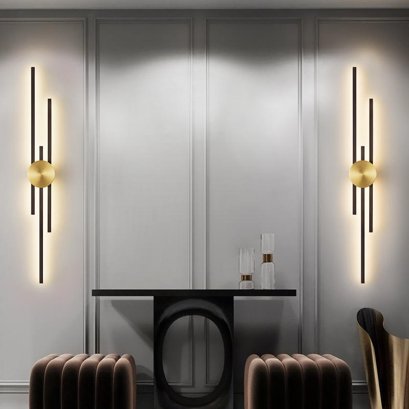Modern wall sconces with gold bulbs on a gray paneled wall above a dining table.