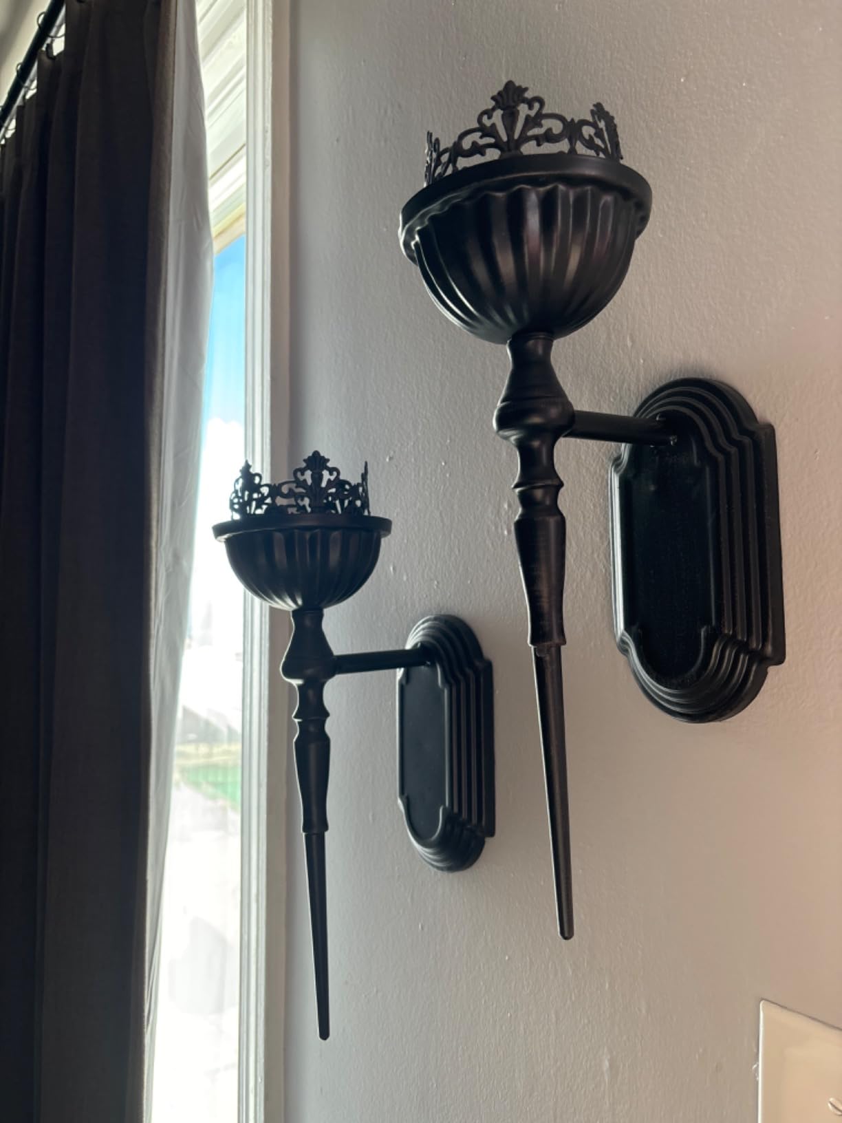 Pair of ornate black wall sconces on a white wall.