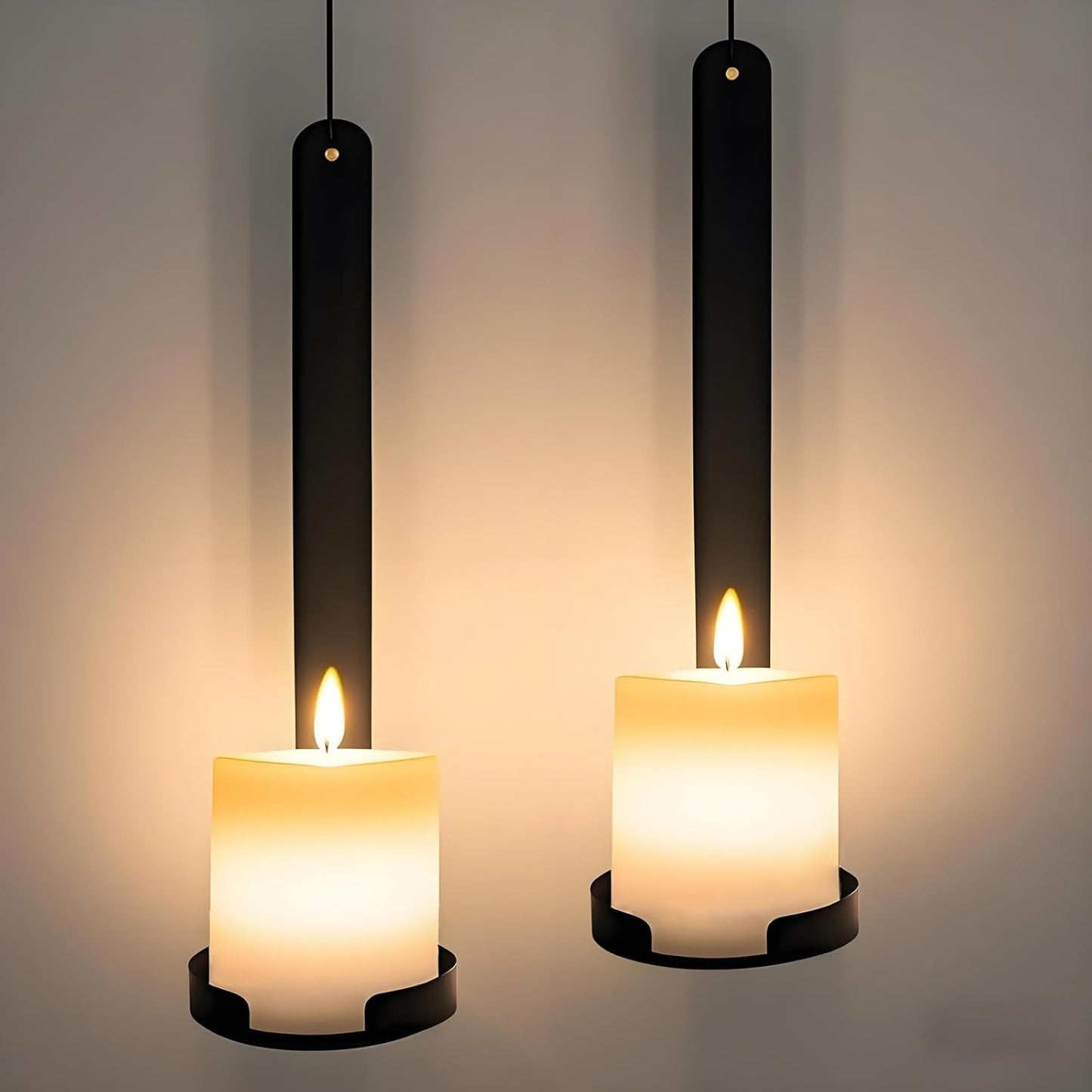 Two hanging candles with black holders on a neutral background