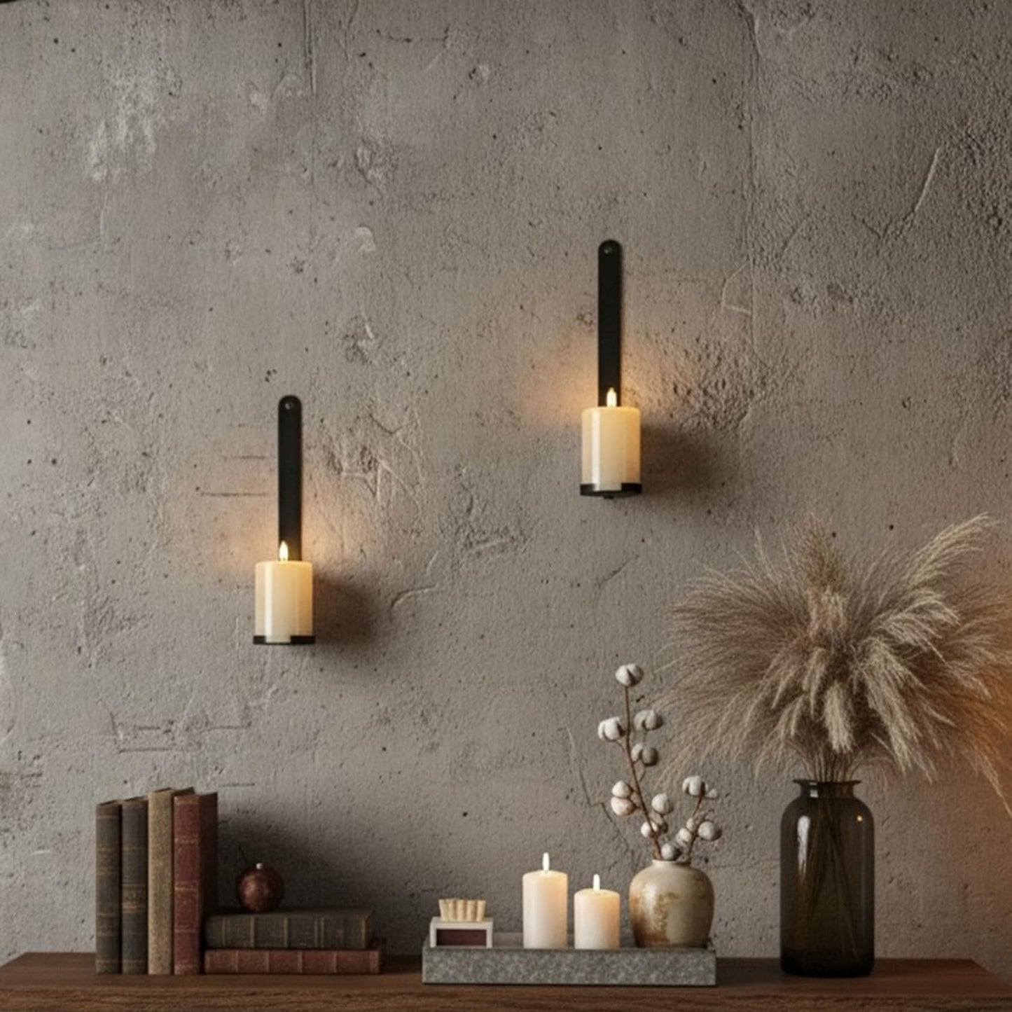 Two wall-mounted candle holders with candles on a textured wall, books, and decorative items on a shelf.