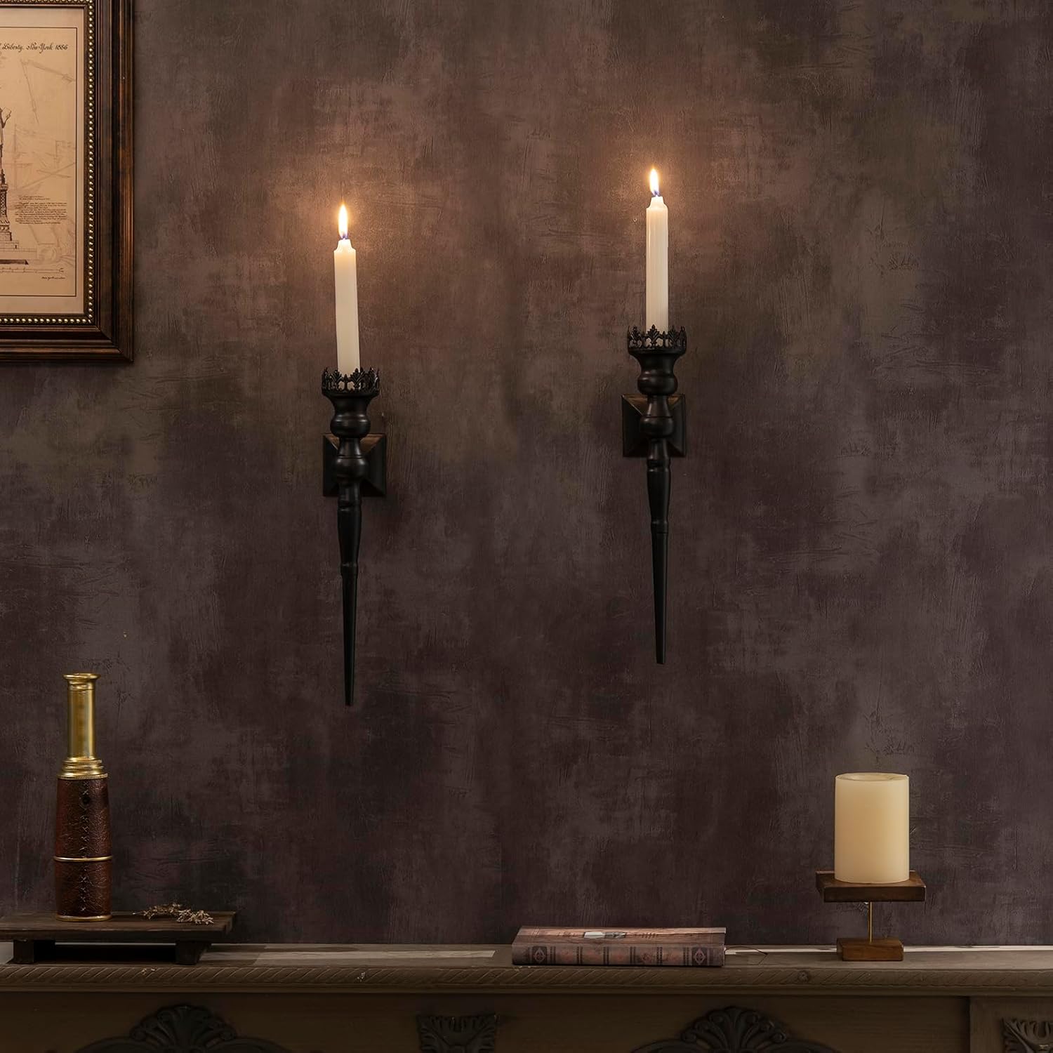 Two wall-mounted candle sconces on a textured wall with decorative items below.