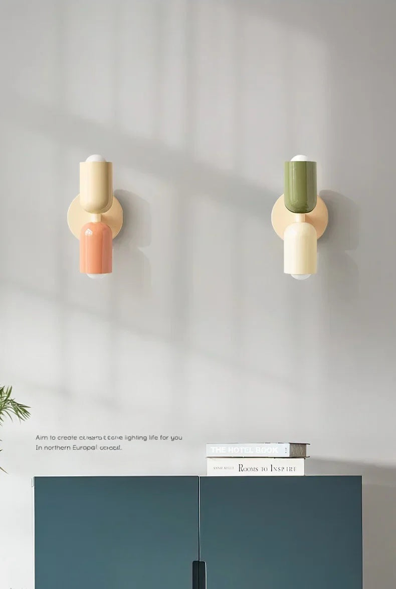 Two wall-mounted lights with colorful shades on a gray wall.