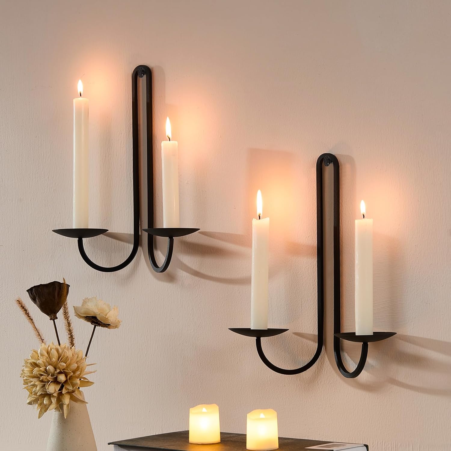 Wall-mounted candle holder with lit candles on a neutral wall.