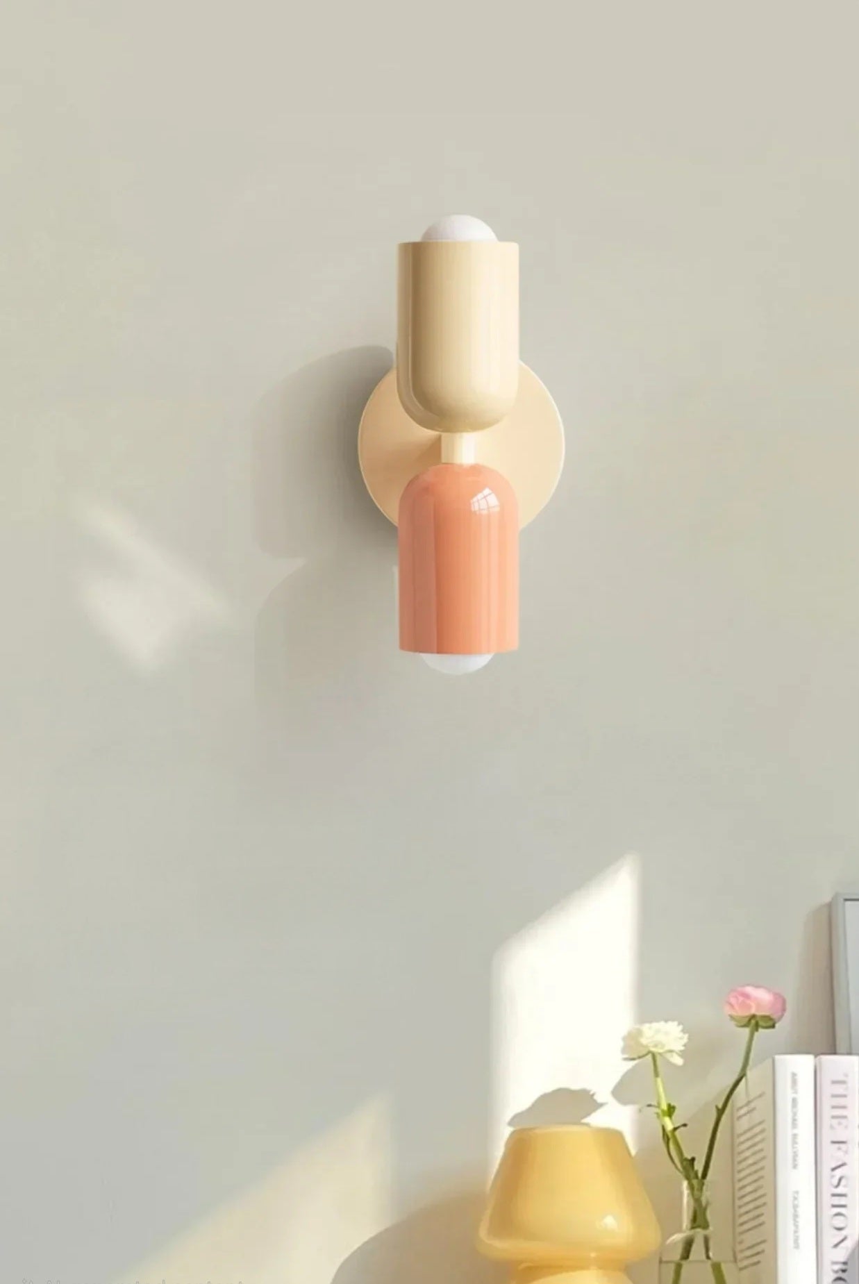 Wall-mounted lamp with a beige and pink design on a light gray wall.