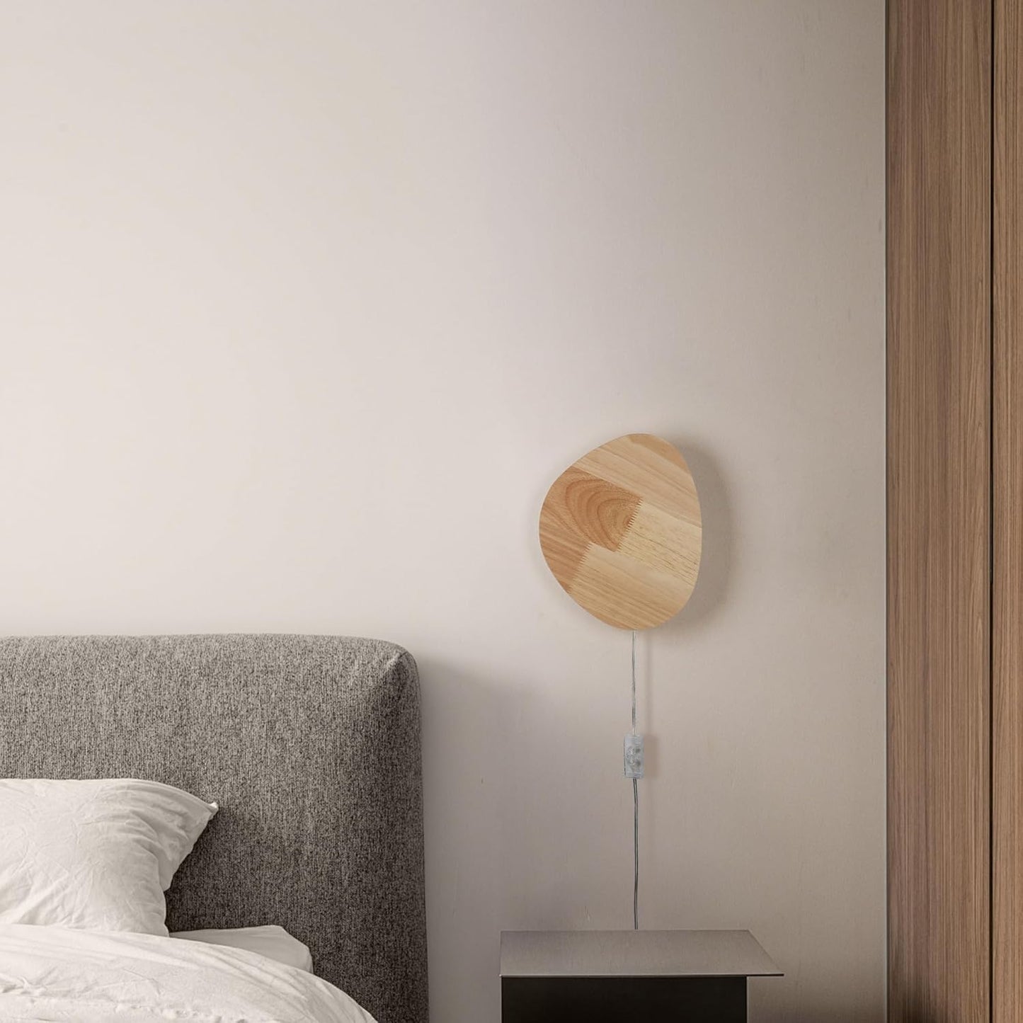 Wooden wall-mounted lamp on a neutral wall next to a bed